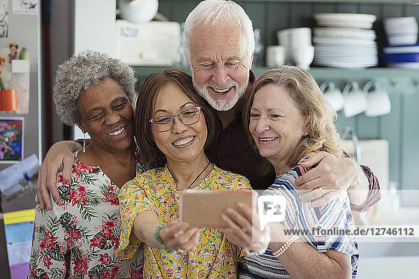 Active senior friends taking selfie with camera phone