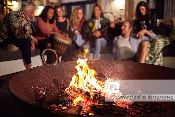 Friends hanging out  playing music on patio next to fire pit