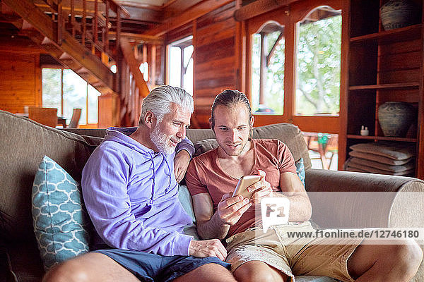 Father and son using smart phone on cabin sofa
