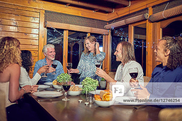 Friends celebrating  drinking red wine and enjoying dinner in cabin