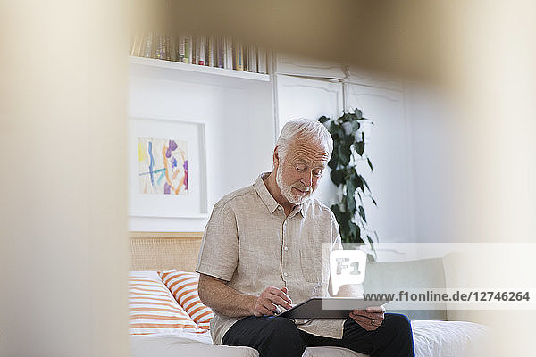 Senior man using digital tablet on bed