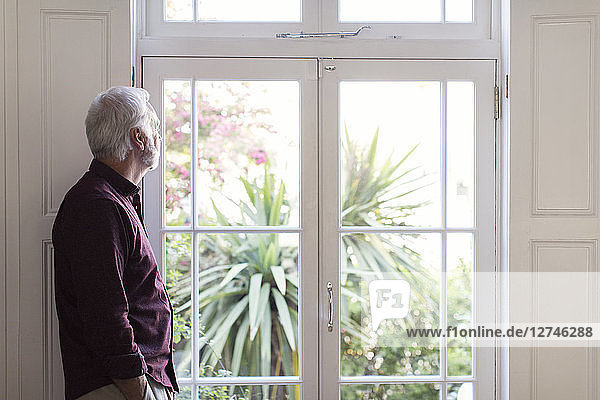 Thoughtful senior man looking out window