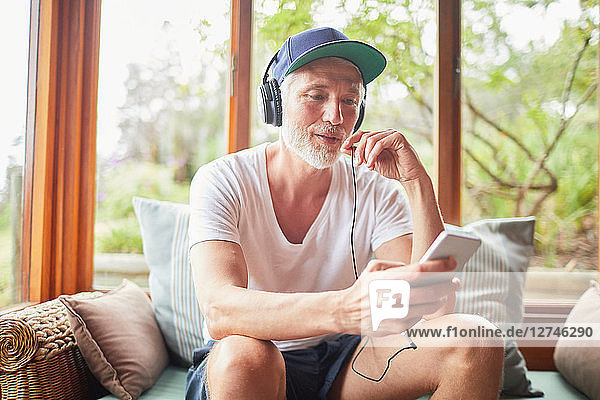 Man with headphones and mp3 player listening to music in living room