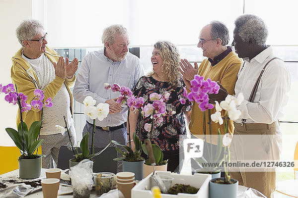 Active senior men clapping for female instructor in flower arranging class