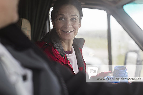 Smiling woman drinking coffee in motor home