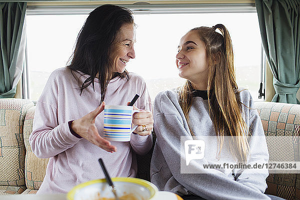 Glückliche Mutter und Tochter genießen heiße Schokolade im Wohnmobil