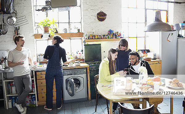 Junge erwachsene Mitbewohner genießen das Frühstück in der Wohnungsküche