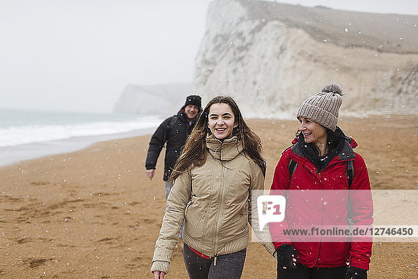 Affectionate mother and daughter walking on snowy winter beach