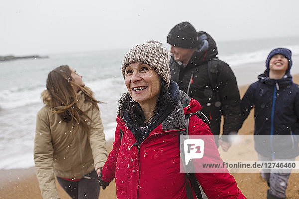 Snow falling over happy family on winter beach