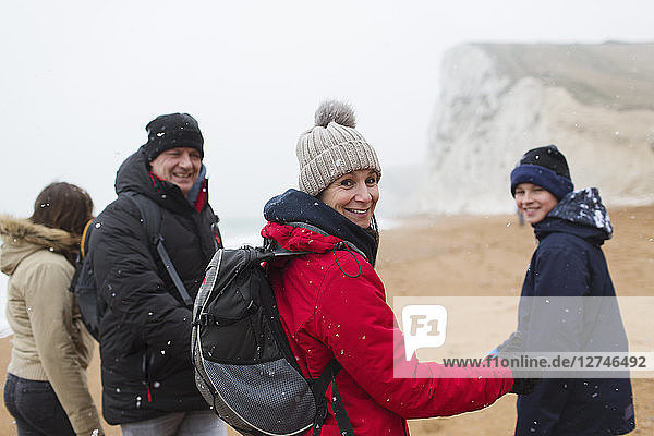 Portrait smiling family in warm clothing on snowy winter beach