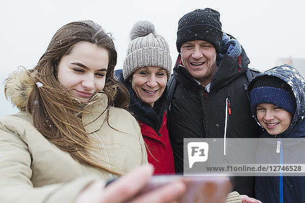 Schnee fällt auf lächelnde Familie  die ein Selfie macht