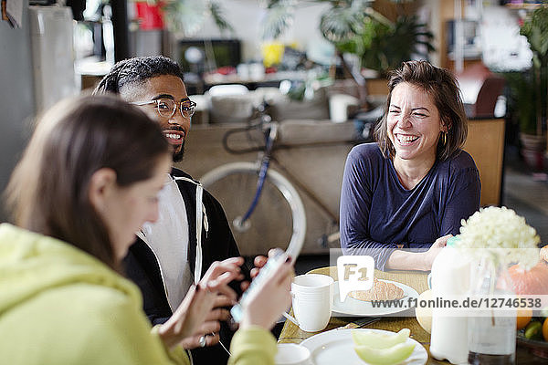Young adult roommate friends enjoying breakfast at apartment kitchen table