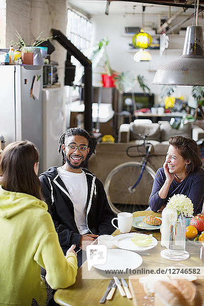 Junge erwachsene Mitbewohner und Freunde unterhalten sich am Frühstückstisch in der Wohnung