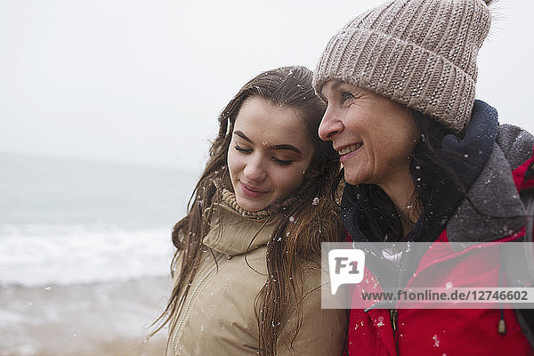 Affectionate mother and daughter on snowy winter beach