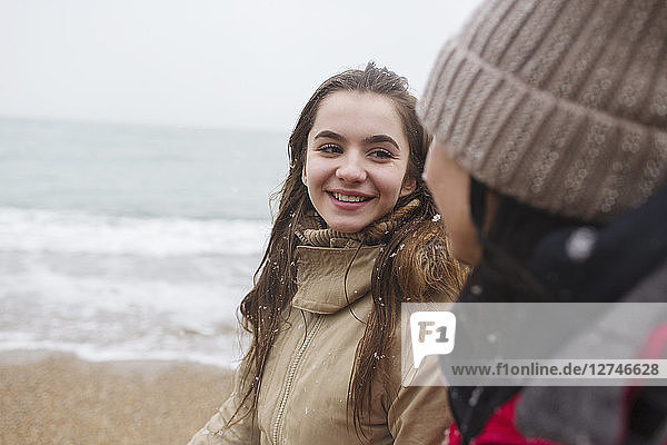 Mother and daughter walking on snowy winter beach
