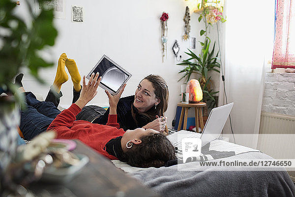 Junge Frauen  die sich auf dem Bett mit Tablet und Laptop entspannen