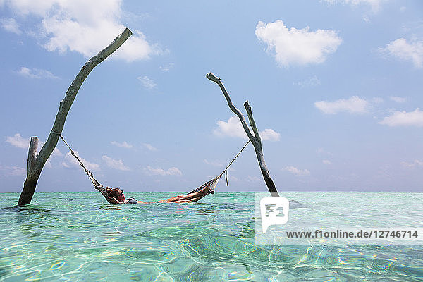 Frau liegt in Hängematte über dem ruhigen Ozean  Malediven  Indischer Ozean