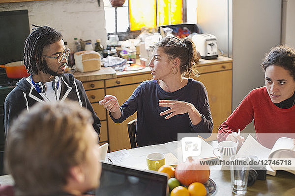 Junge College-Studenten  die am Küchentisch in einer Wohnung lernen und sich unterhalten