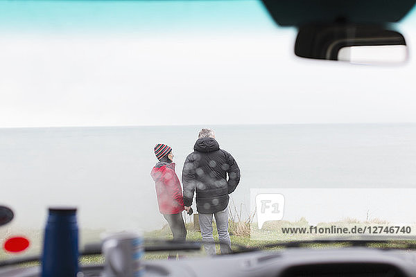 Ein Paar steht vor einem Wohnmobil auf einer Klippe mit Blick auf den Ozean