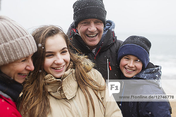 Schneefall über glücklicher Familie in warmer Kleidung