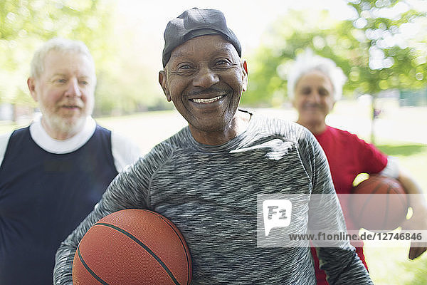 Portrait confident  smiling active senior men friends with basketballs in park