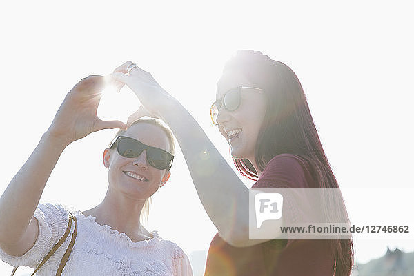 Affectionate lesbian couple forming heart-shape with hands