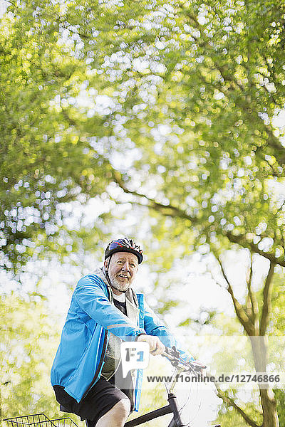 Portrait confident active senior man riding bike in park