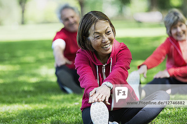Happy active senior woman stretching leg in park
