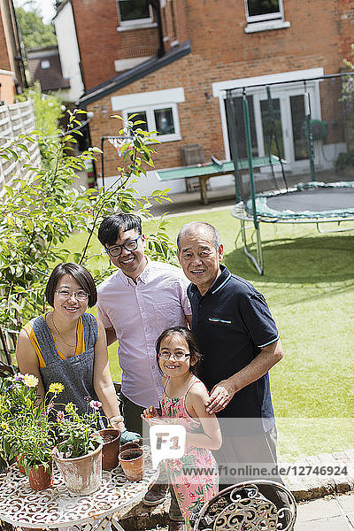 Portrait smiling multi-generation family gardening  potting flowers in sunny yard