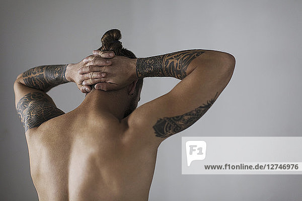 Rear view bare chested hipster man with tattoos