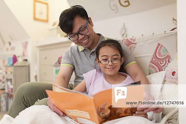 Father and daughter reading book in bedroom