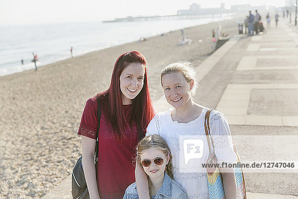 Portrait smiling lesbian couple and daughter on sunny beach boardwalk