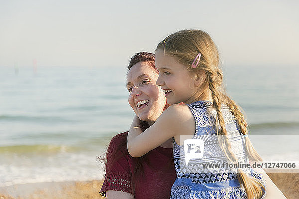 Affectionate mother holding daughter on sunny beach
