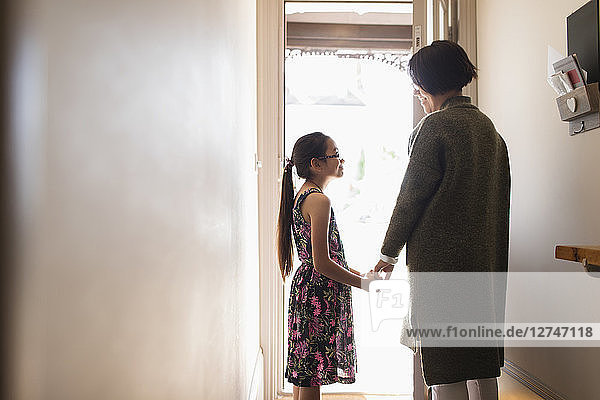 Affectionate mother and daughter holding hands in doorway