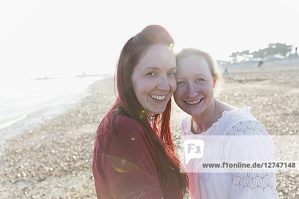 Portrait smiling  affectionate lesbian couple on sunny beach