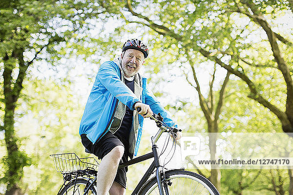 Portrait smiling active senior man riding bike in park