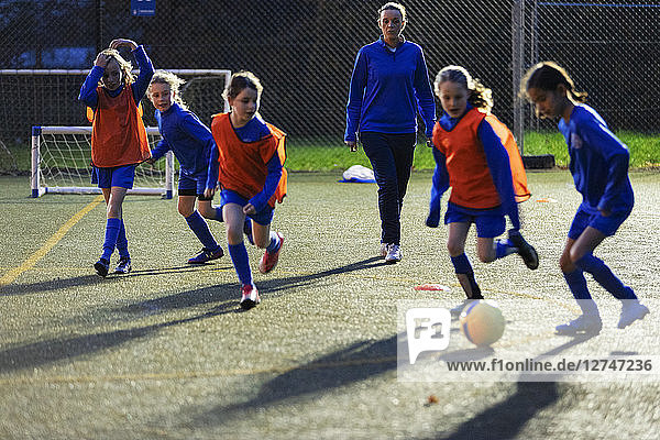 Fußballtrainer beobachtet Mädchen beim Training auf dem Feld