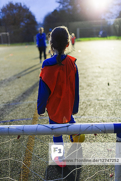 Mädchen spielt Fußball auf einem Feld bei Nacht
