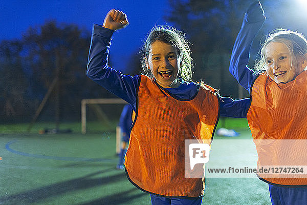 Porträt begeisterter Mädchenfußballerinnen  die nachts auf dem Spielfeld jubeln