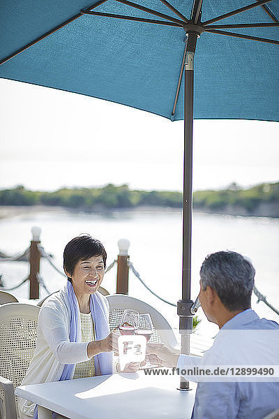 Japanisches Seniorenpaar bei einem Drink am Meer
