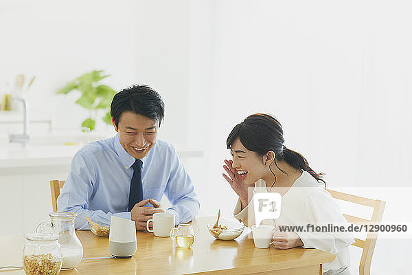 Japanisches Paar in der Küche mit Smart-Home-Assistent