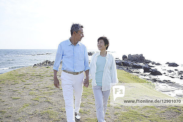 Japanese senior couple having fun by the sea