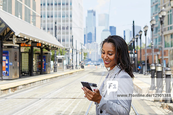 Geschäftsfrau benutzt Handy im Stadtbahnhof