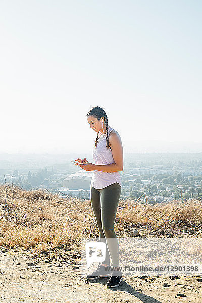Frau benutzt Mobiltelefon auf einem Hügel  Los Angeles  USA
