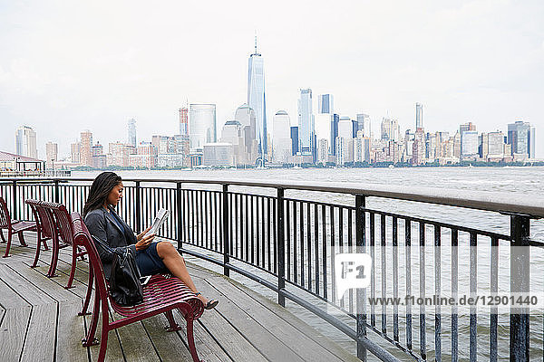 Geschäftsfrau beim Zeitungslesen  im Hintergrund die Skyline von New York City