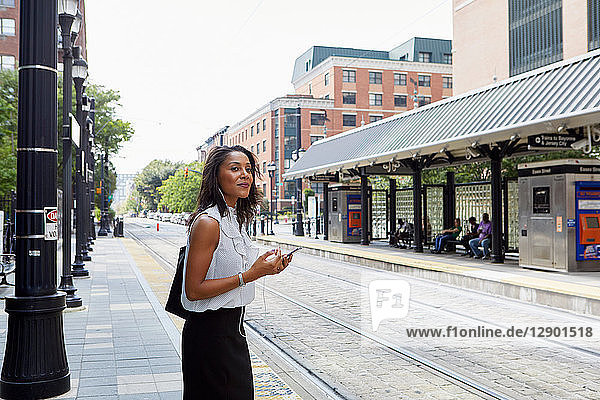 Geschäftsfrau benutzt Handy im Stadtbahnhof