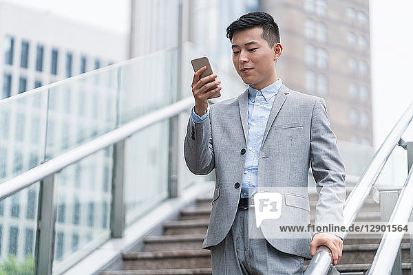 Junger Geschäftsmann betrachtet Smartphone auf Stadttreppe  Shanghai  China