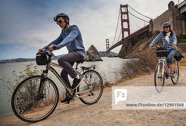 Tourists cycling Golden Gate Bridge in background San Francisco USA