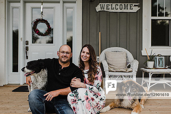 Couple and their two dogs sitting on porch
