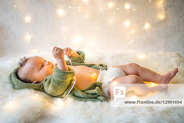 Baby boy lying on furry rug playing with decorative lights